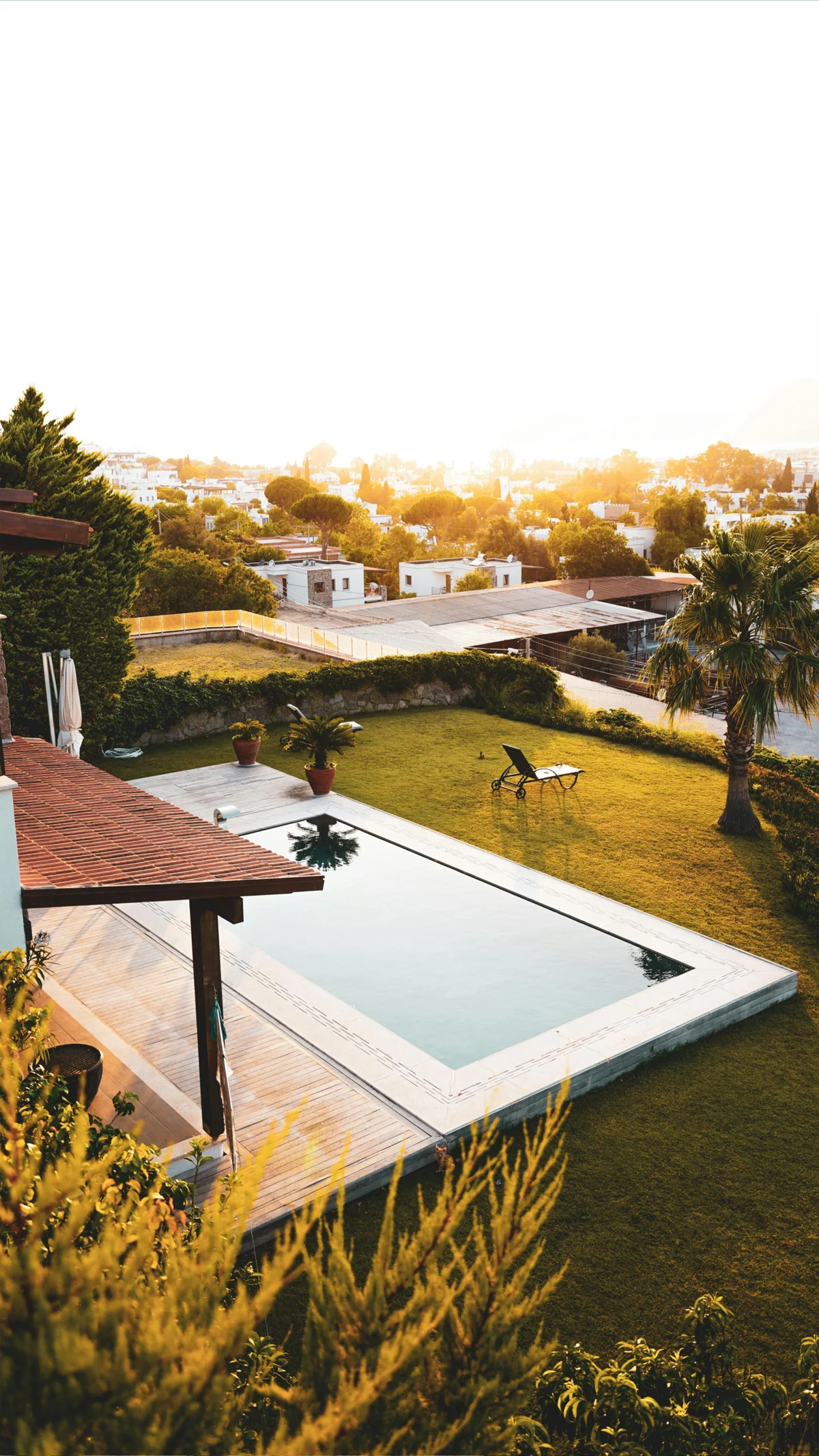 Jardín y piscina junto a una vivienda al atardecer